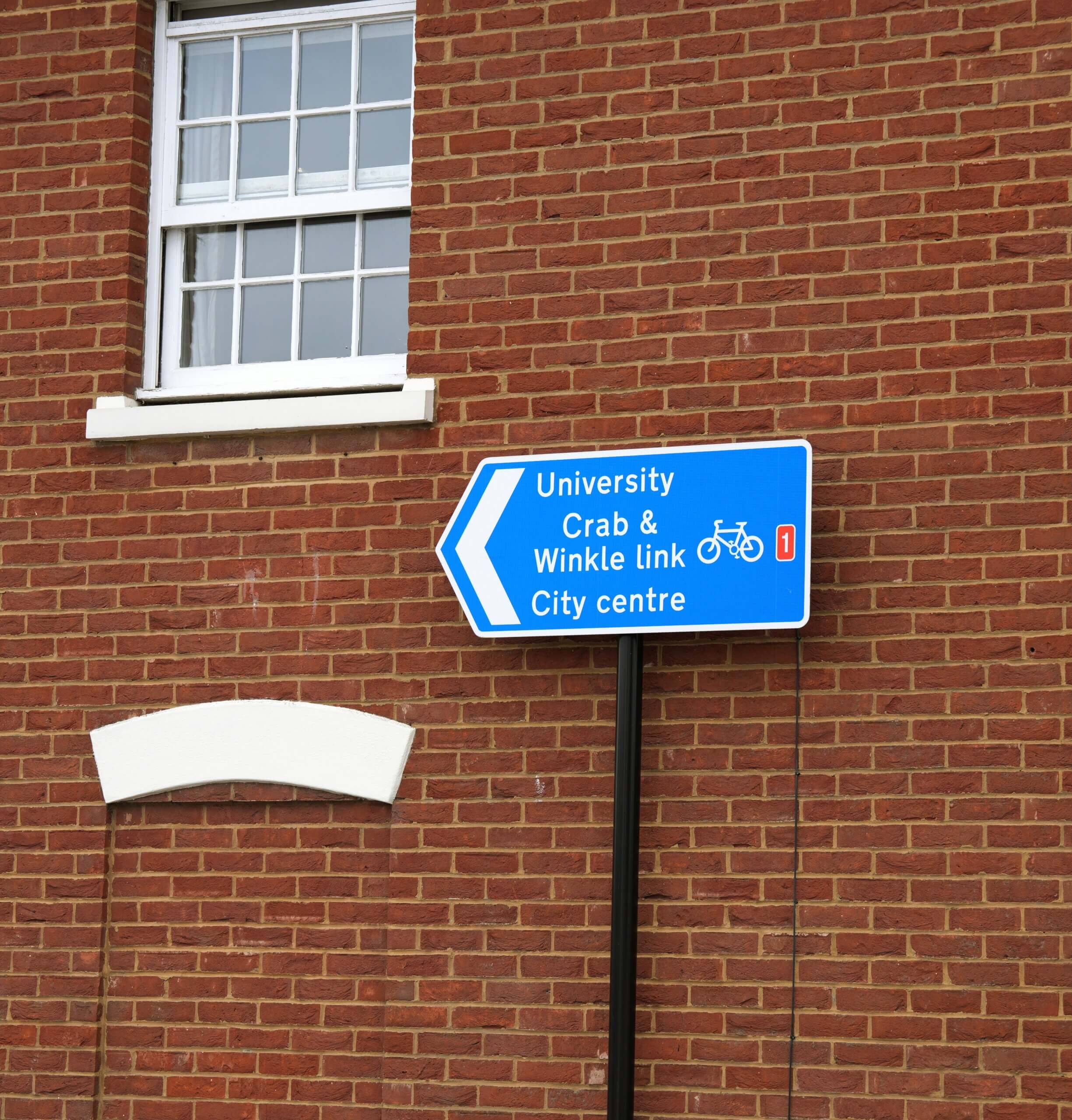 Directional sign pointing towards Canterbury city centre near Kent College.