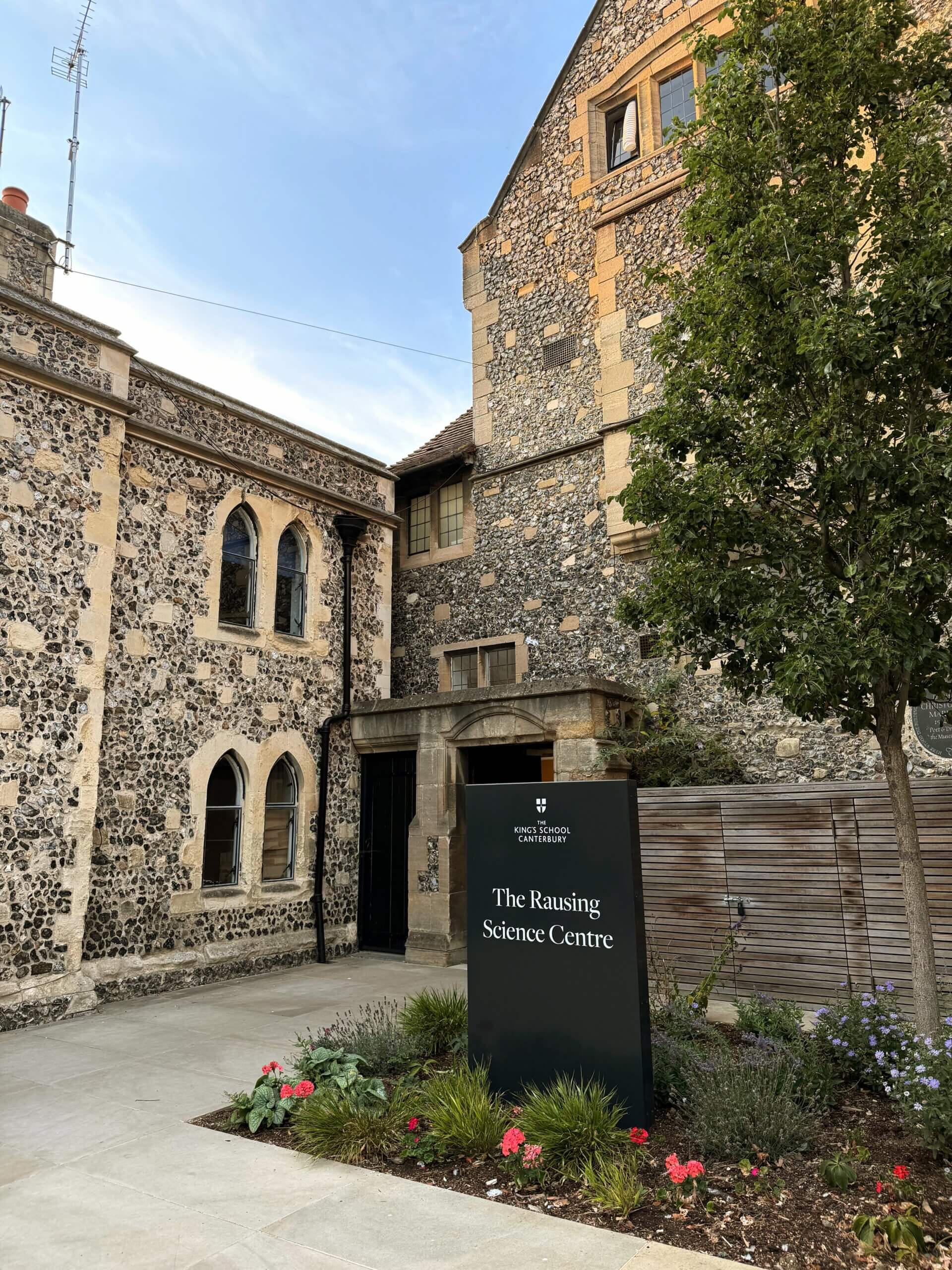 The Rausing Science Centre at The King's School Canterbury, featuring a modern entrance alongside historic flint buildings.